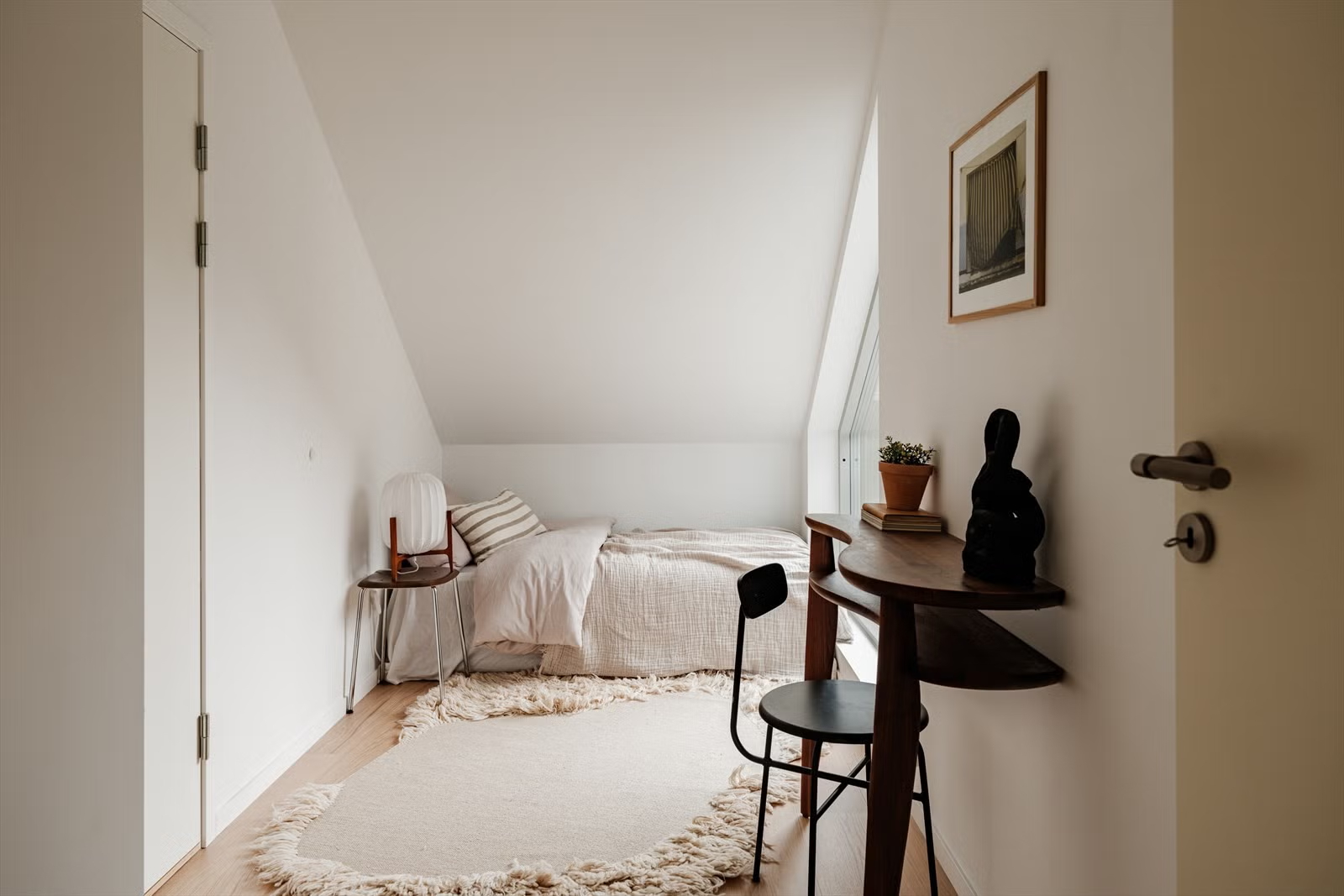 Attic bedroom with sloped ceiling in the Living Under the Sky apartment in Oslo by IK-architects